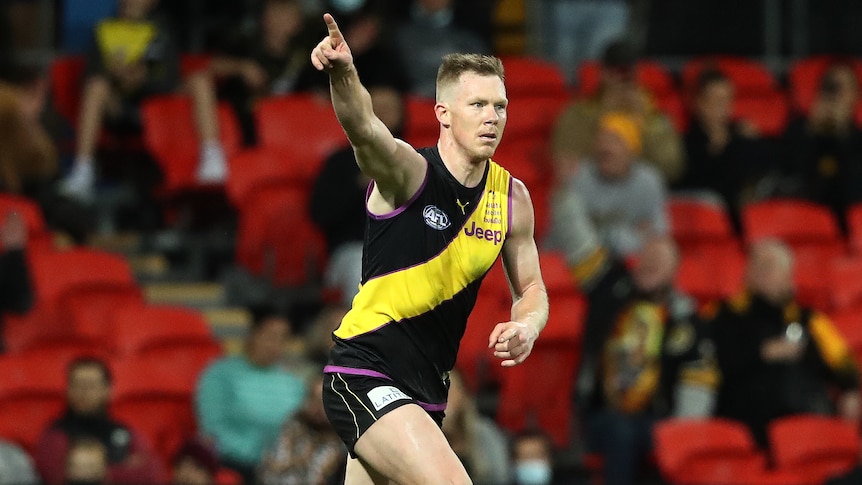 A Richmond AFL player points a finger on his right hand as he celebrates kicking a goal.