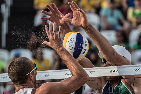Nicholas Lucena of USA smashes the ball into Brazilian beach volleyball player Alison Cerutti