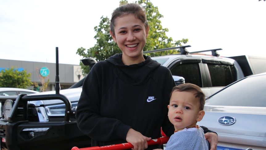 A young woman with a child in a shopping trolley.