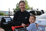 A young woman with a child in a shopping trolley.