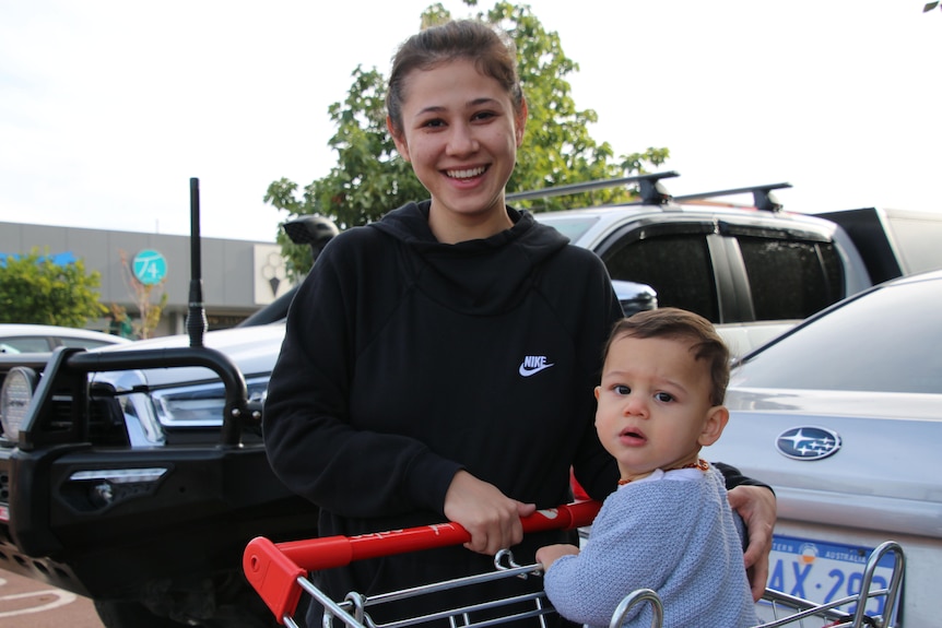 A young woman with a child in a shopping trolley.