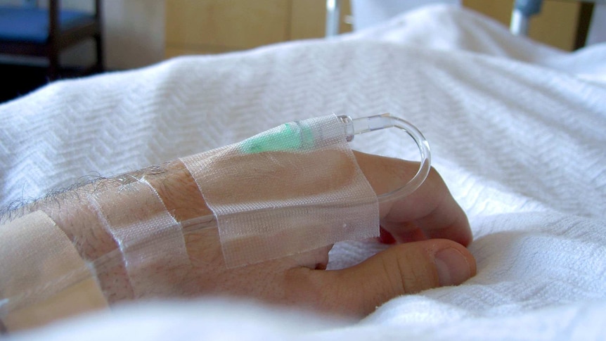 A hand rests on a hospital bed.