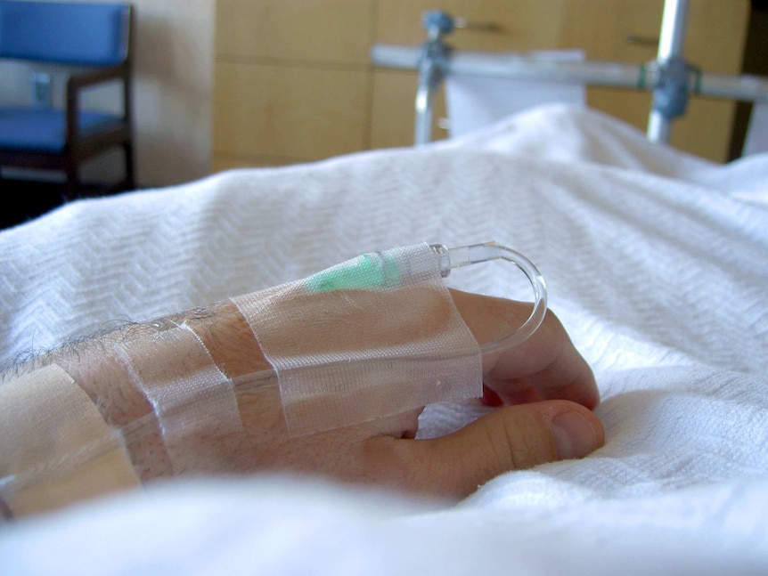 A hand rests on a hospital bed.