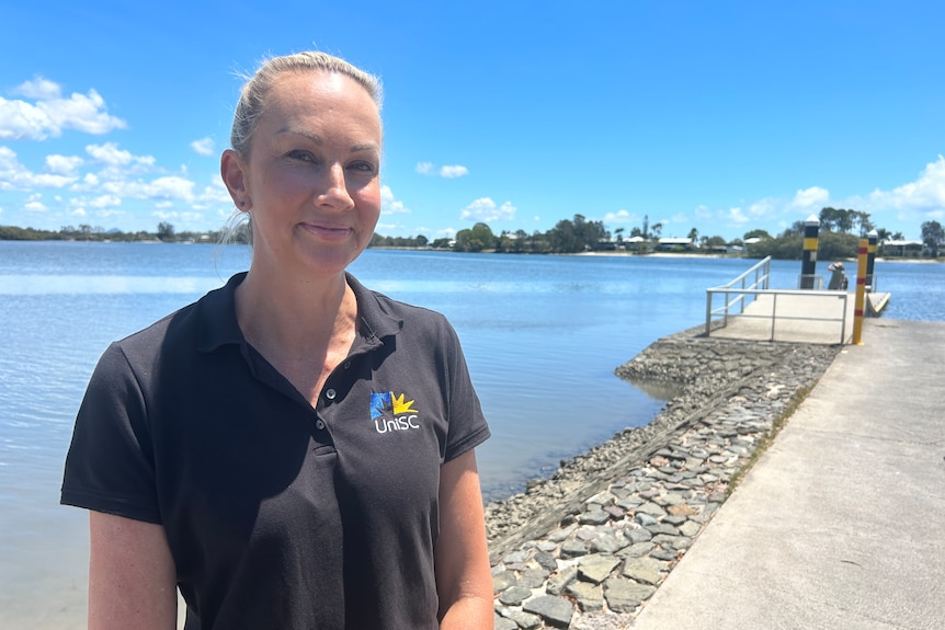 Woman standing at a boatramp with water in background