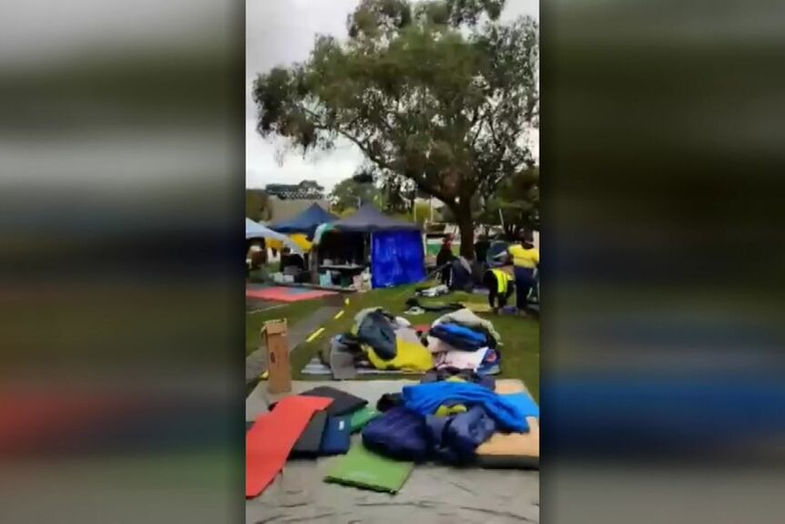 User generated video screengrab of camping gear on the ground with tents in the background. 