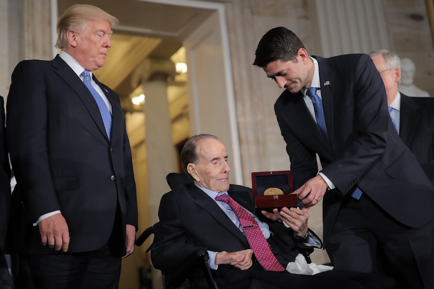 Bob Dole seated receives a medal in a box.