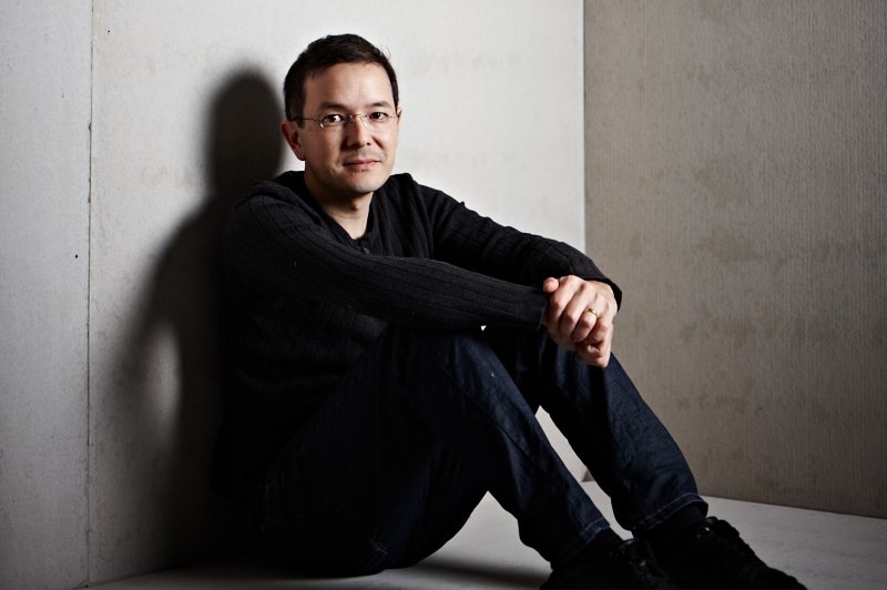 Author and illustrator Shaun Tan sitting on the ground wearing a black shirt.