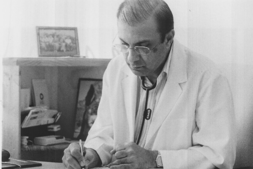 Doctor with his head down writing at a desk