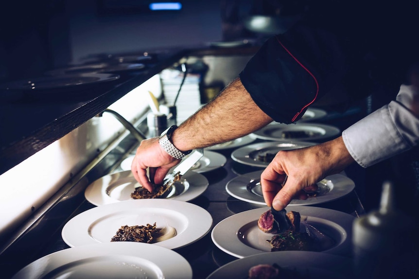 Two men serve up food in a restaurant for story on taking sick leave