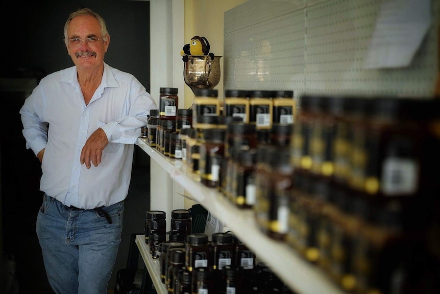 Peter Norris stands next to jars of honey