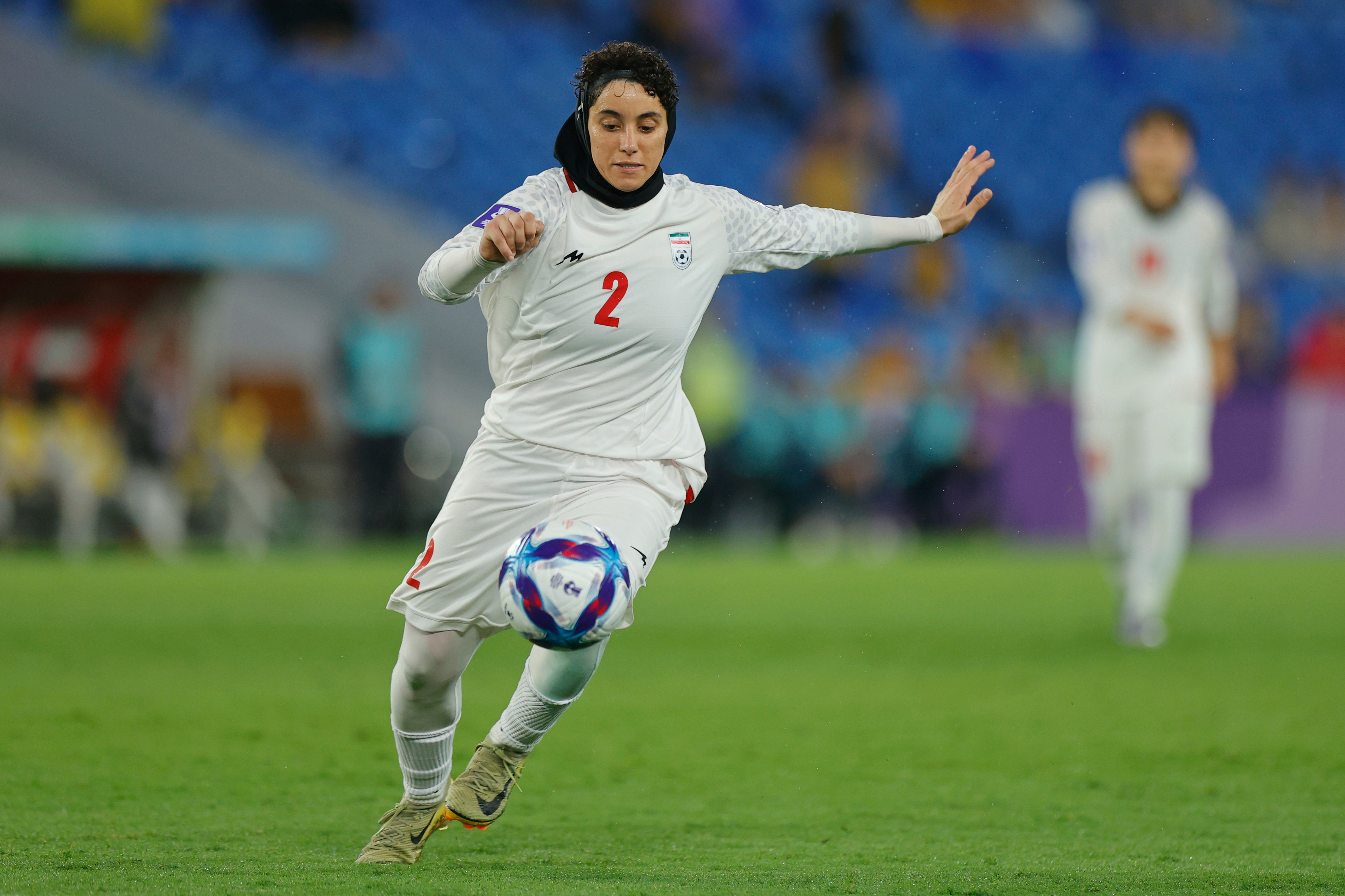 Um membro da seleção iraniana de futebol feminino corre com a bola durante um jogo