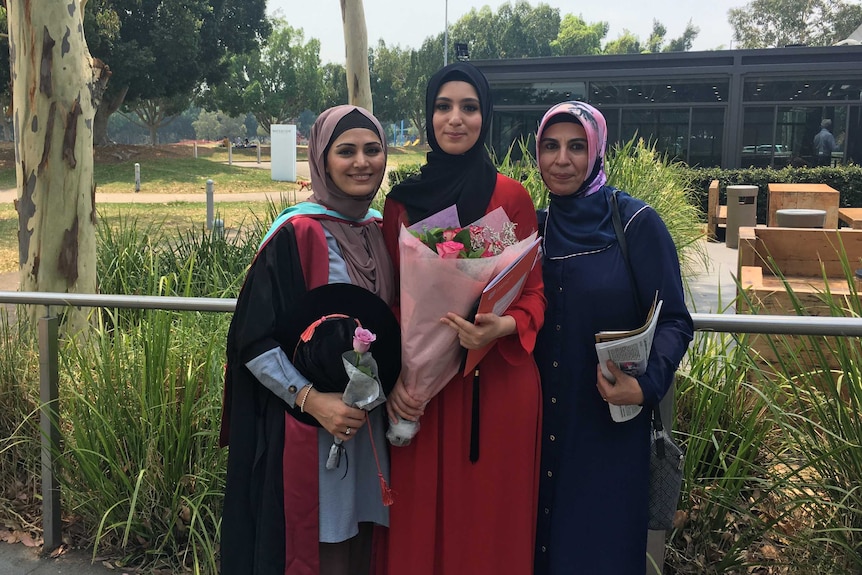 Mahsheed Ansari wearing a graduate gown, with two other Muslim women in graduate gowns.