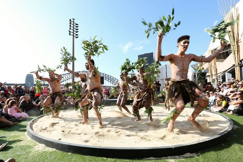 A group of male Indigenous dancers perform outside the Sydney Opera House.