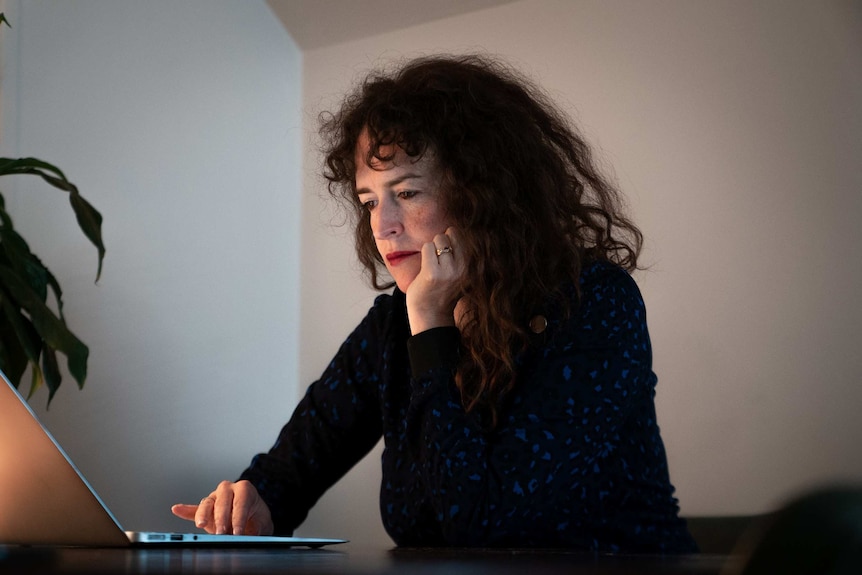 A woman sits at a desk and types on a computer