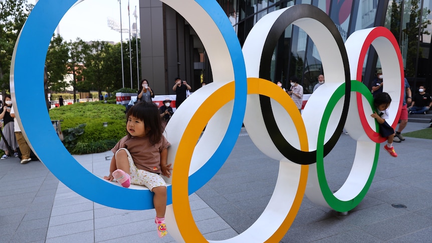 A child sits on giant Olympic Rings.