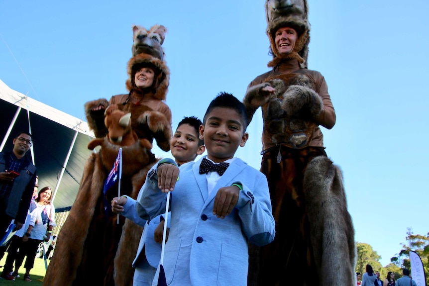 Young boys in suits smile and pose with adults in kangaroo costumes