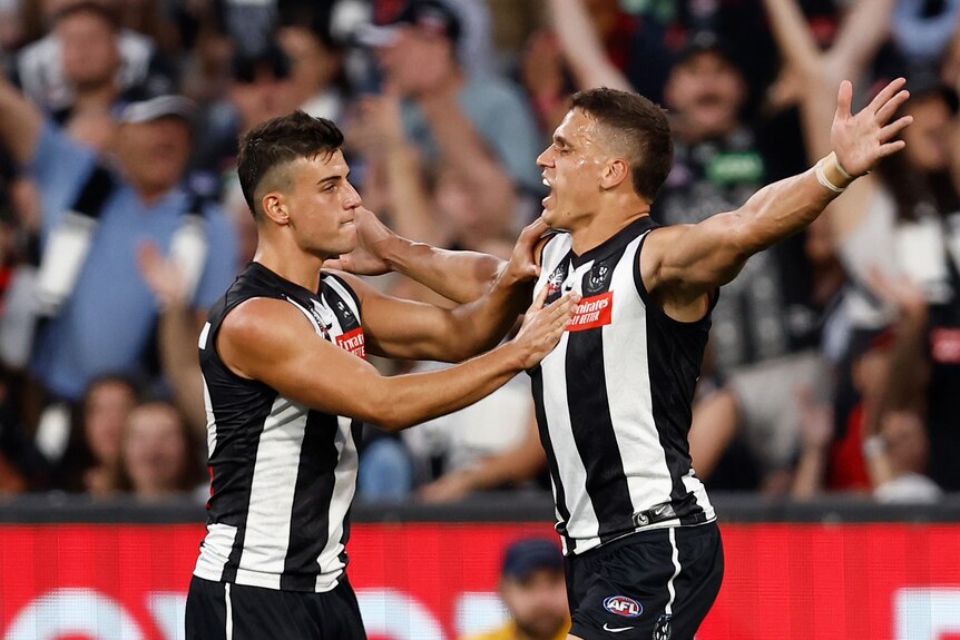 Two Collingwood players celebrate a goal together.