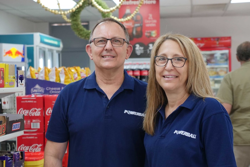 A couple stand in a supermarket smiling.