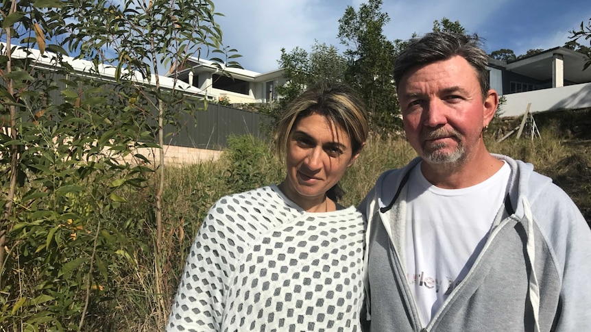 Couple stands on an overgrown block of land.