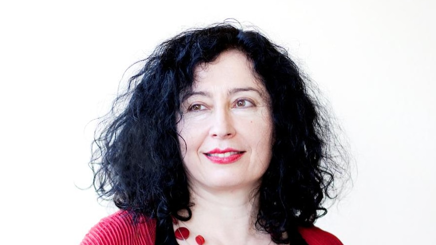 Image of a woman with dark curly hair dressed in black and red, with a red necklace and red lipstick.