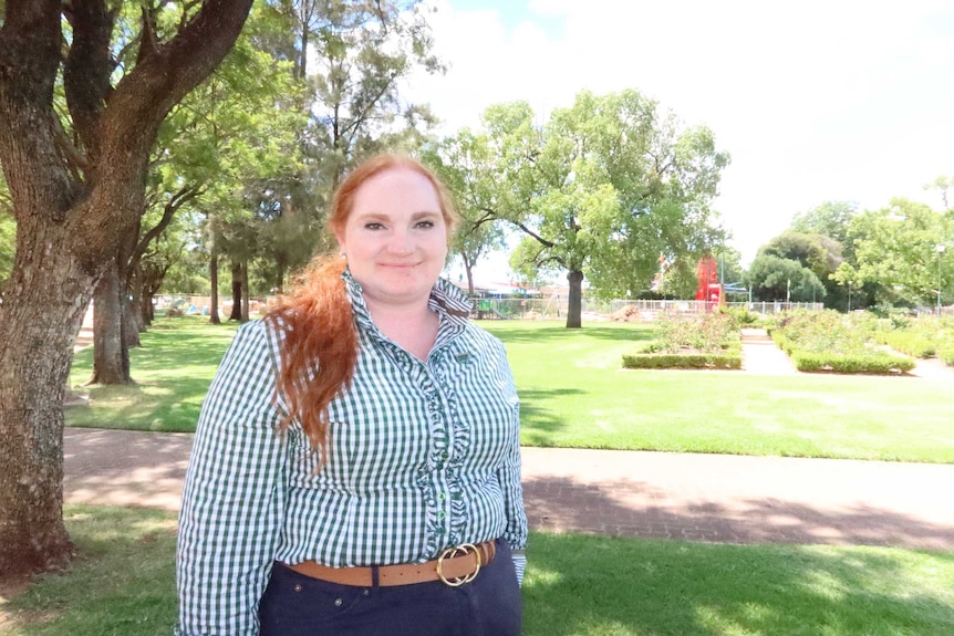 A woman in a checked shirt smiles at the camera.