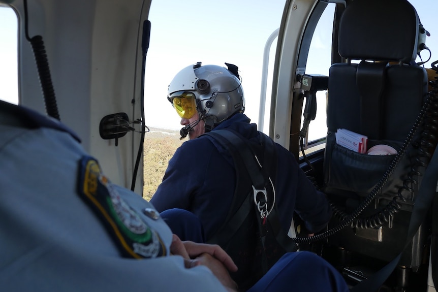 Man observes out of the door of a helicopter