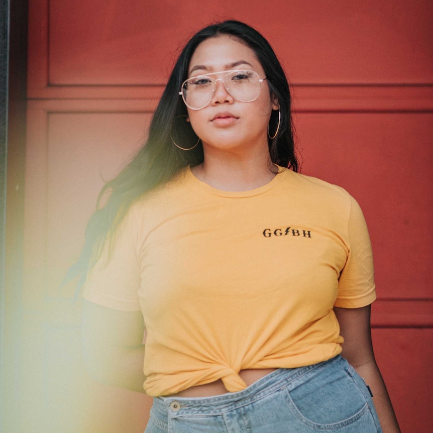 A woman wearing a yellow tshirt that has a knot in it