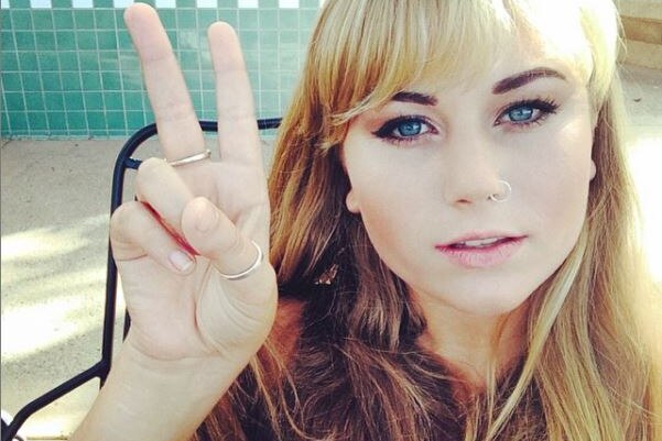 A girl with a golden blonde fringe gives a peace sign