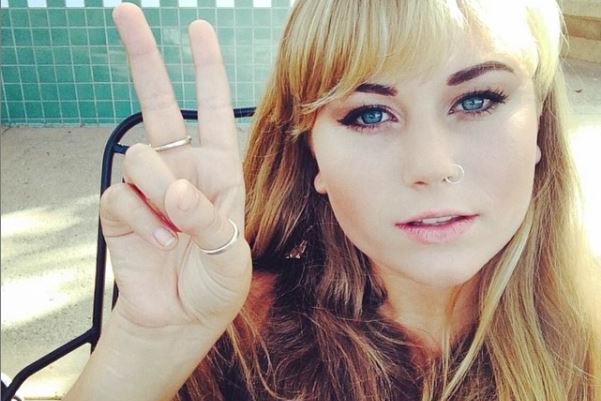 A girl with a golden blonde fringe gives a peace sign