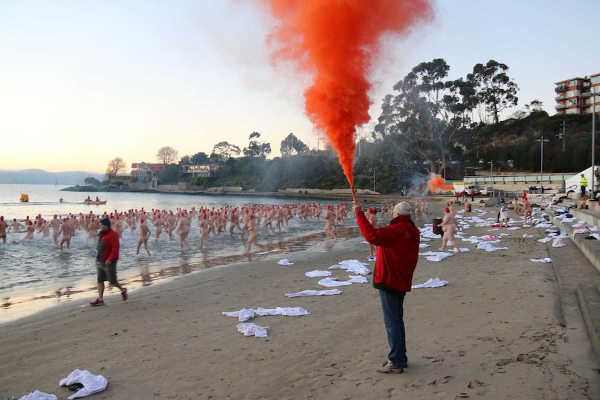 Flares mark the start of the Dark Mofo nude winter swim in Hobart. 