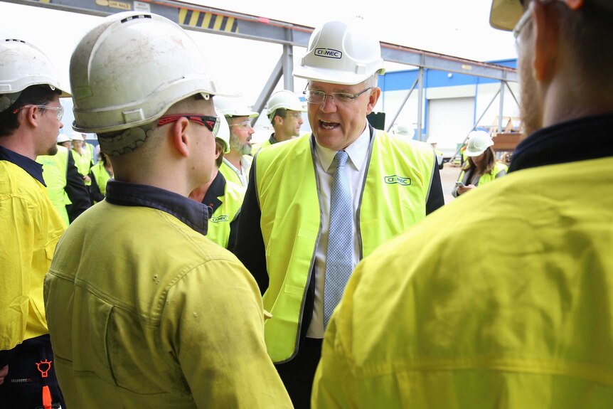 Dressed in high-vis and a hard hat, Mr Morrison meets with workers also wearing hard hats