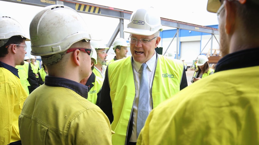 Dressed in high-vis and a hard hat, Mr Morrison meets with workers also wearing hard hats