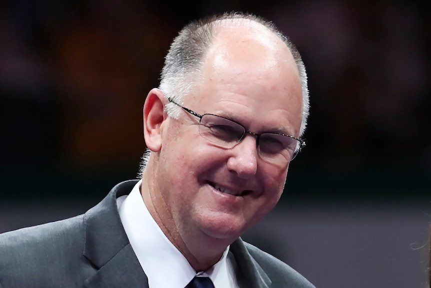 A man in a suit and glasses smiling 