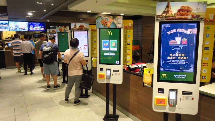 A row of white self-service kiosks at a restaurant.
