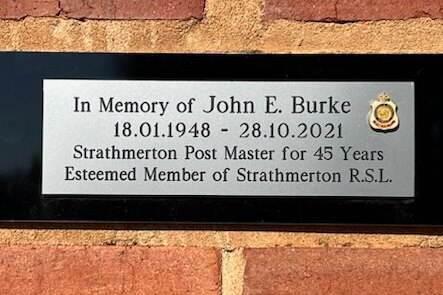 A plaque at Strathmerton Public Hall placed in memory of John Bourke, who served as the Strathmerton postmaster for 45 years.