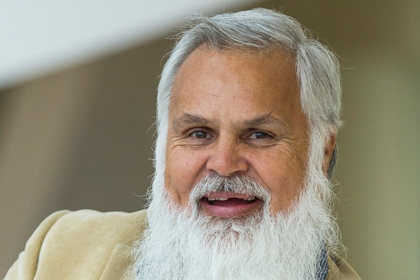 A man with a beautiful grey beard smiles widely at the camera.