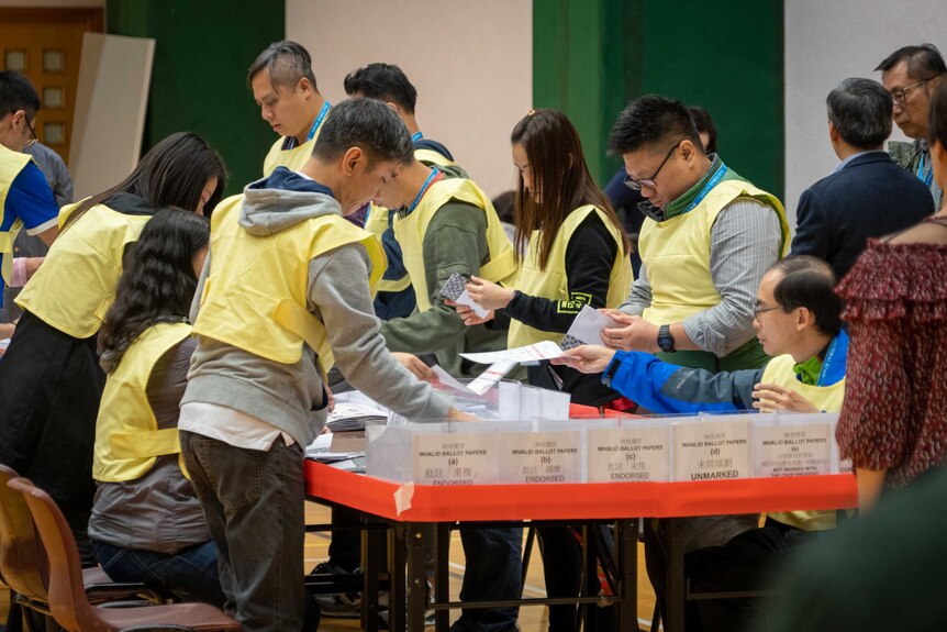 People in yellow vests counting ballots at a desk