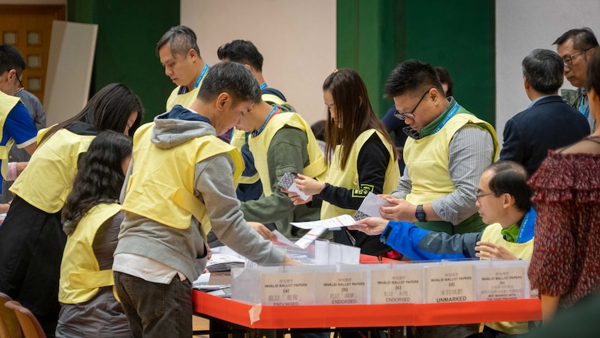 People in yellow vests counting ballots at a desk