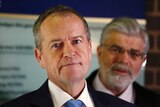 Close-up of Bill Shorten with Kim Carr standing behind him, out of focus
