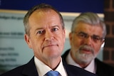 Close-up of Bill Shorten with Kim Carr standing behind him, out of focus