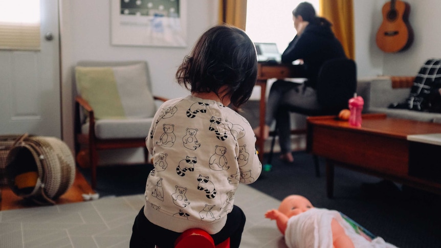 A young girl sits on a stool while an adult woman works in the background, for a story about energy bill shock.