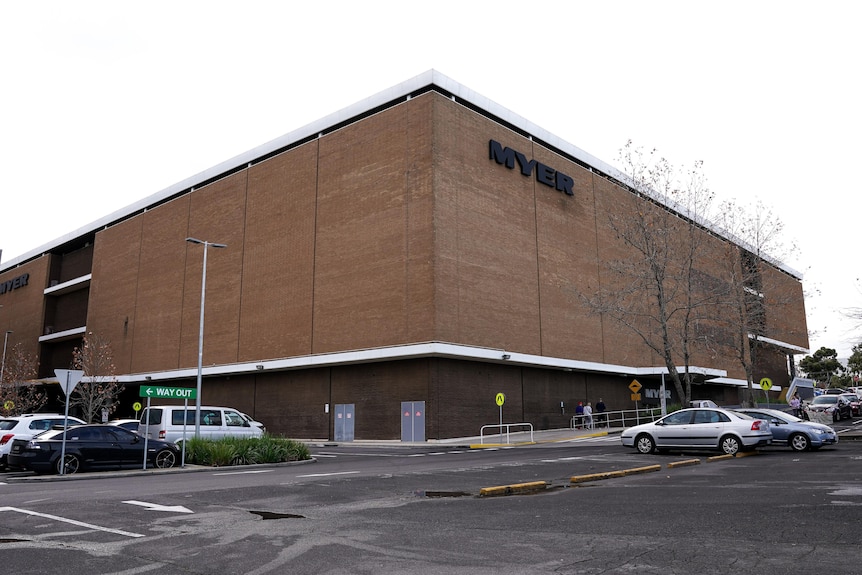 A large brown building with no windows with a car park out the front