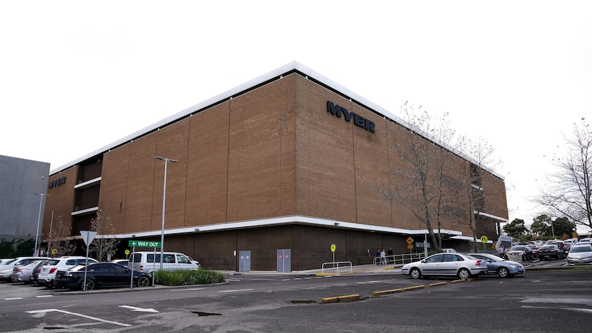 A large brown building with no windows with a car park out the front