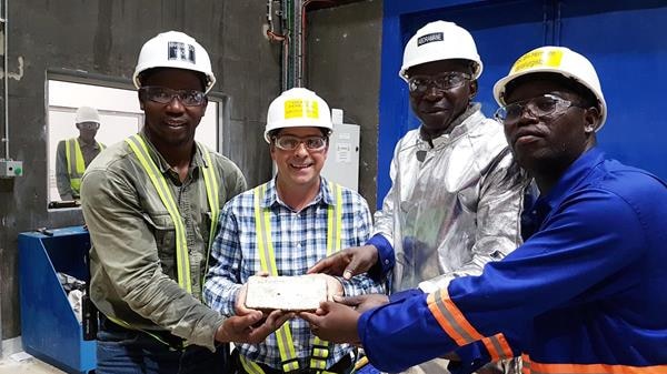 Men holding a freshly poured gold bar