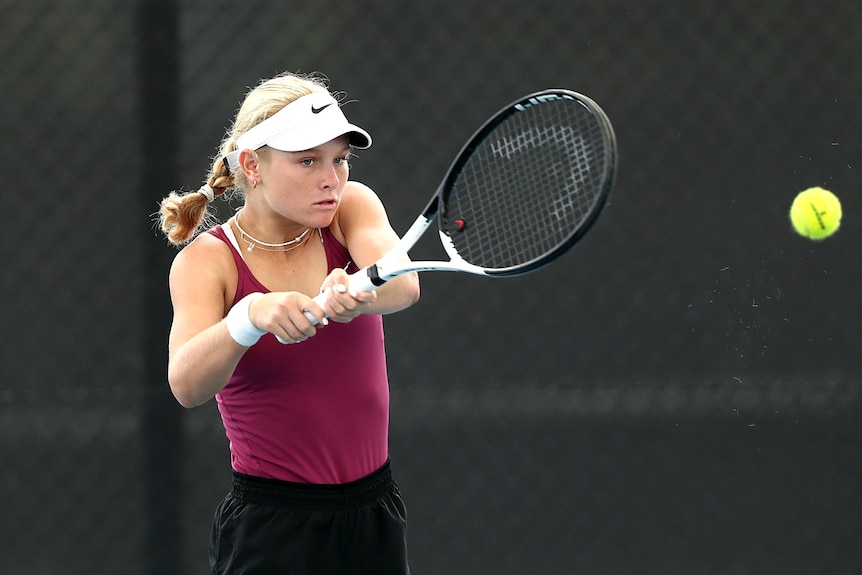 A young tennis player completes a backhand
