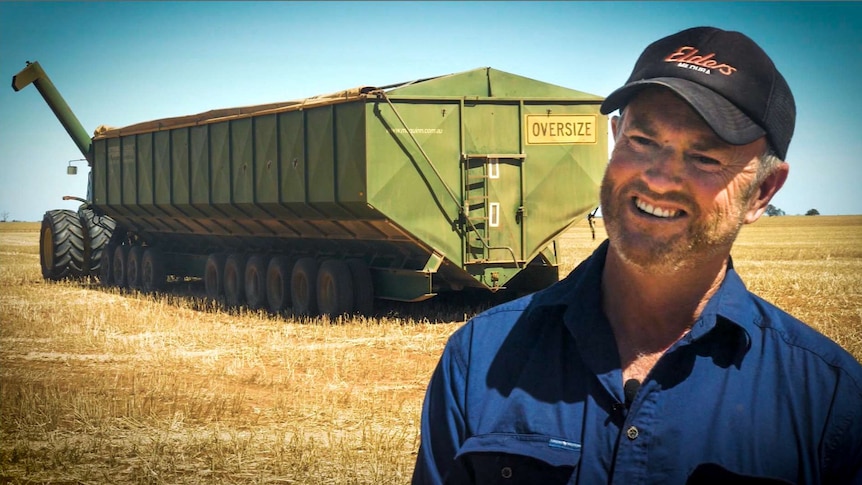 A grain farmer stands in front of a chaser bin on his wheat property