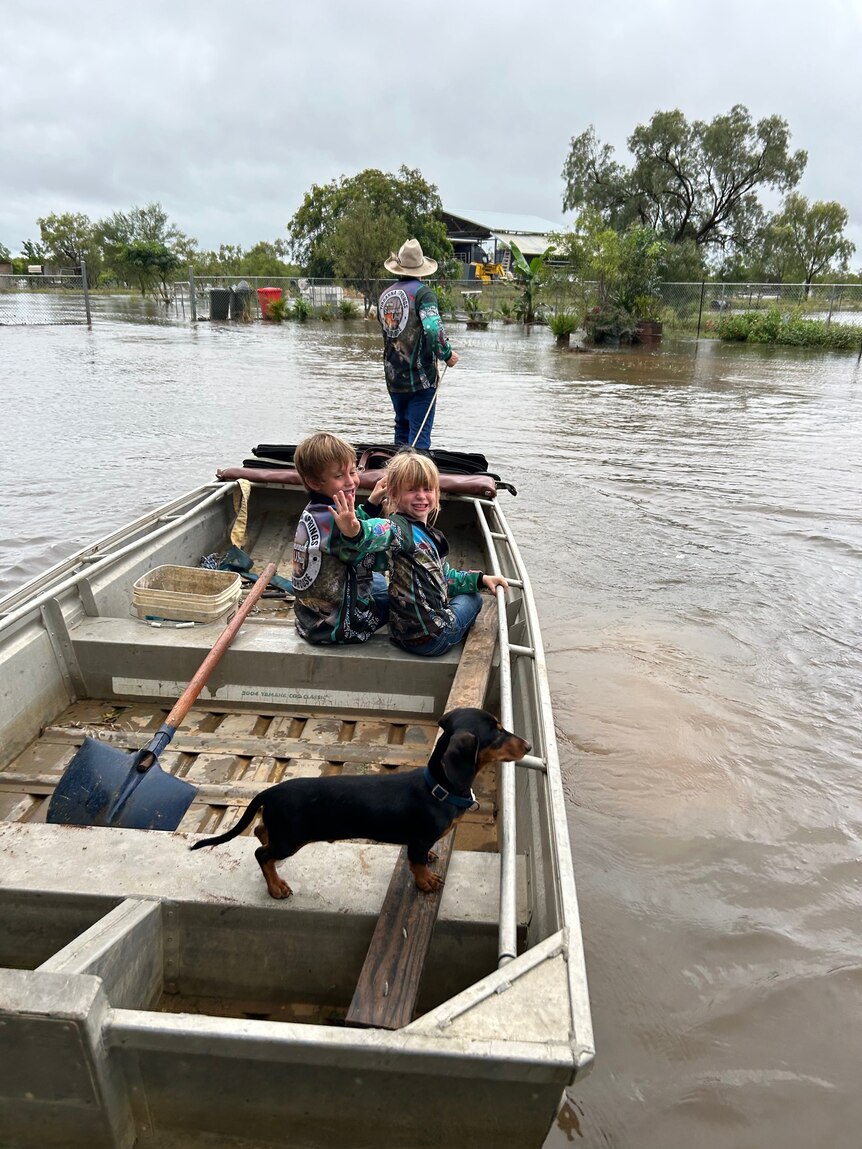 Two young kids in a tin boat in floodwater