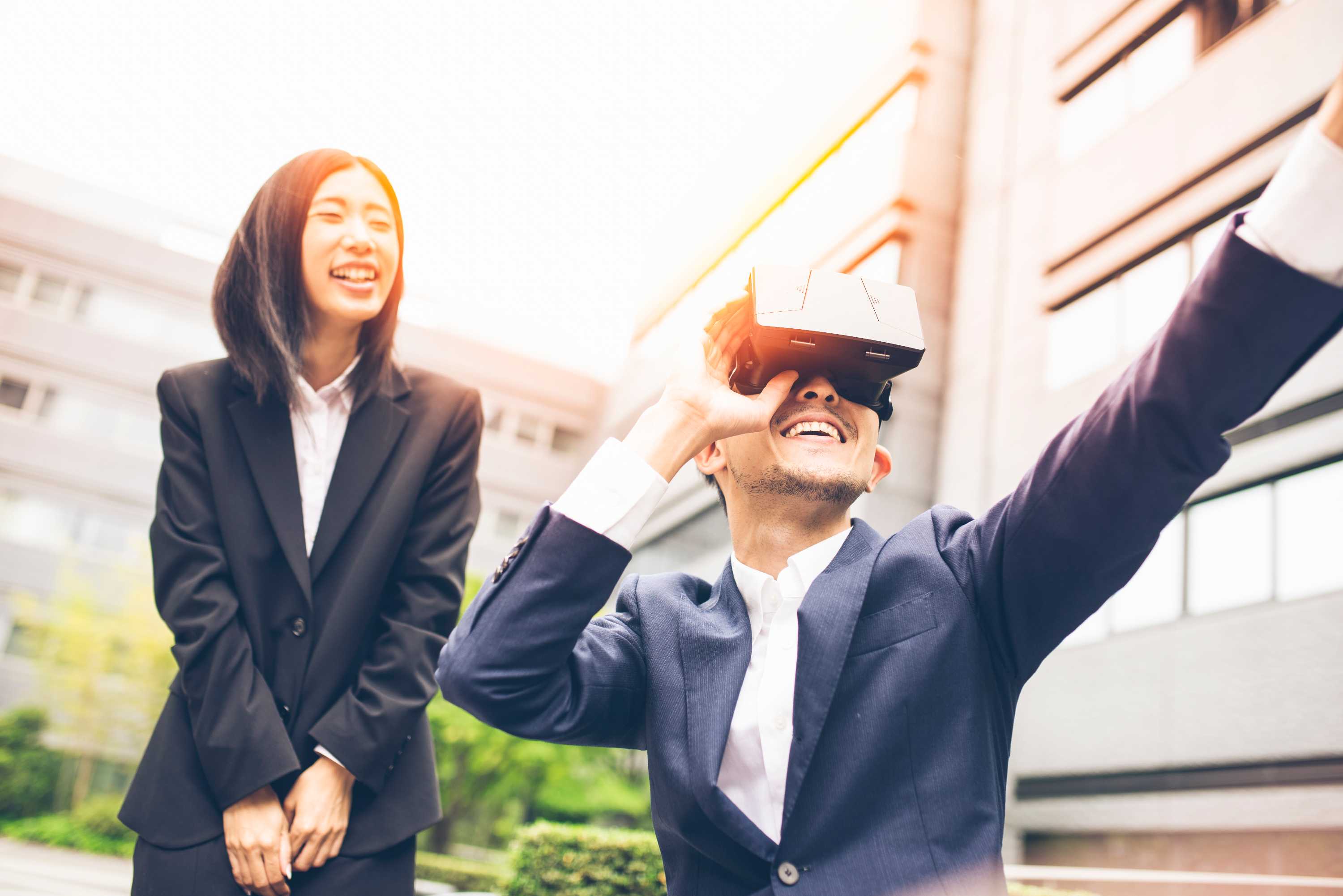 Two office workers in suits playing a virtual reality video game.