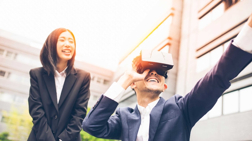 Two office workers in suits playing a virtual reality video game.