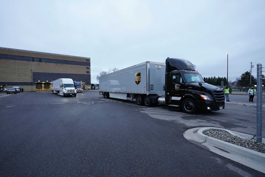 Two large trucks departing a warehouse.